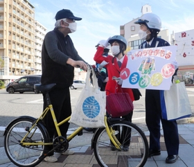 自転車利用者にヘルメットの着用を呼びかける長田署員ら＝３月２０日午後、神戸市長田区