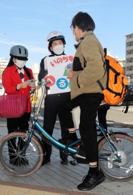 自転車利用者にヘルメットの着用を呼びかける長田署員ら＝３月２０日午後、神戸市長田区