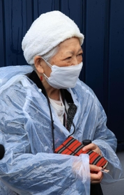 事故現場を訪れた藤崎光子さん。手元には、いつも持ち歩く亡き長女の写真があった＝２５日午前８時４６分、尼崎市久々知西町２（撮影・鈴木雅之）