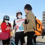 自転車利用者にヘルメットの着用を呼びかける長田署員ら＝３月２０日午後、神戸市長田区