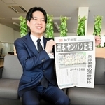 １１年前の神戸新聞号外を手に笑顔の飯田卓也さん＝淡路市役所