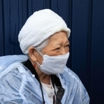 事故現場を訪れた藤崎光子さん。手元には、いつも持ち歩く亡き長女の写真があった＝２５日午前８時４６分、尼崎市久々知西町２（撮影・鈴木雅之）