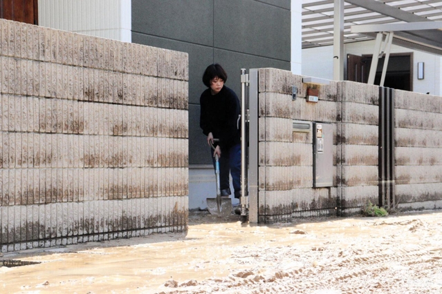 泥が入り込み、片付けに追われる住民＝８日午前１０時２５分、伊丹市荒牧６
