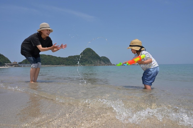 浜辺で水遊びをする親子＝１７日午前、豊岡市竹野町竹野（撮影・斎藤雅志）