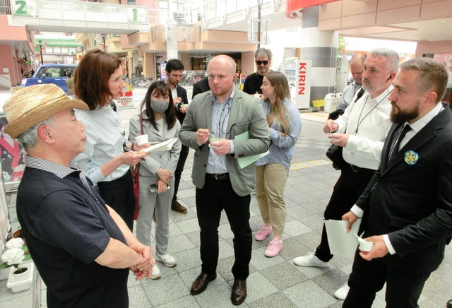 震災の再開発地区で伊東正和さん（左）から話を聞くウクライナの視察団＝２２日午後、神戸市長田区久保町６