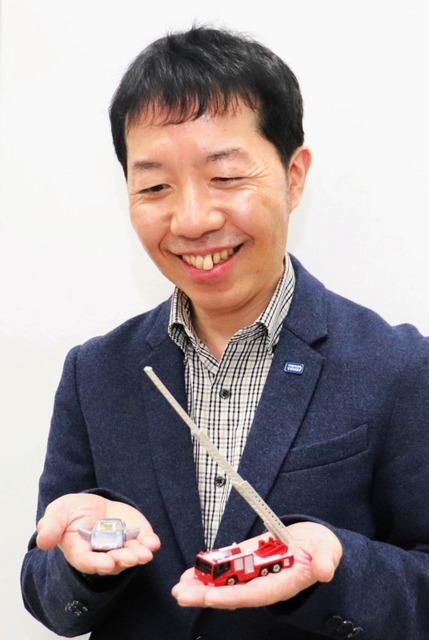 トミカの国内出荷実績１位「日野はしご付消防車」を手にするタカラトミーの遠藤勇希さん＝東京都葛飾区