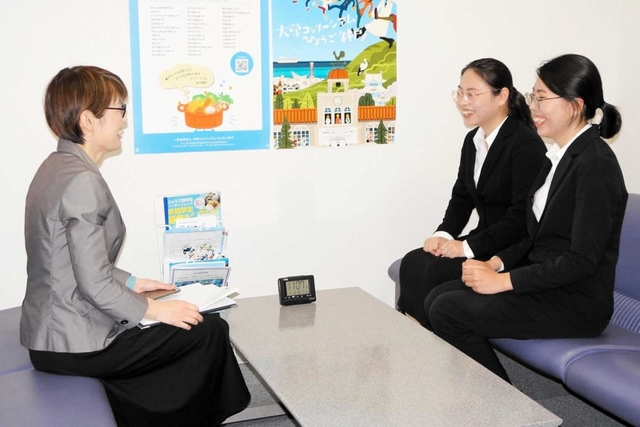 ワンストップ相談窓口の担当者（左）と談笑する外国人留学生の女性２人＝神戸市中央区脇浜町１