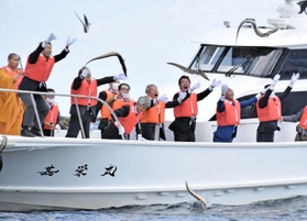 ハモを勢いよく海に投げ入れる「鱧供養祭」の参列者ら＝８日午前、南あわじ市沼島