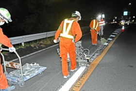 夜間に道路上の区画線を引き直す業者＝西宮市樋ノ口町２