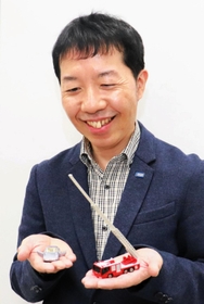 トミカの国内出荷実績１位「日野はしご付消防車」を手にするタカラトミーの遠藤勇希さん＝東京都葛飾区
