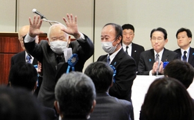 集会で、車いすから立ち上がり、支援者らに手を振る有本明弘さん＝東京都千代田区
