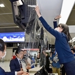 飛沫防止のフィルムを撤去する成田国際空港会社の職員＝８日午前、成田空港