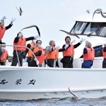 ハモを勢いよく海に投げ入れる「鱧供養祭」の参列者ら＝８日午前、南あわじ市沼島