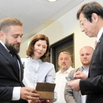 ウクライナ南部ミコライウ市のセルヒー・コレニエフ副市長（左端）から、被害の実相を伝えるため、ロシア軍が放ったミサイルの破片を手渡された久元喜造神戸市長＝２２日午前、神戸市役所