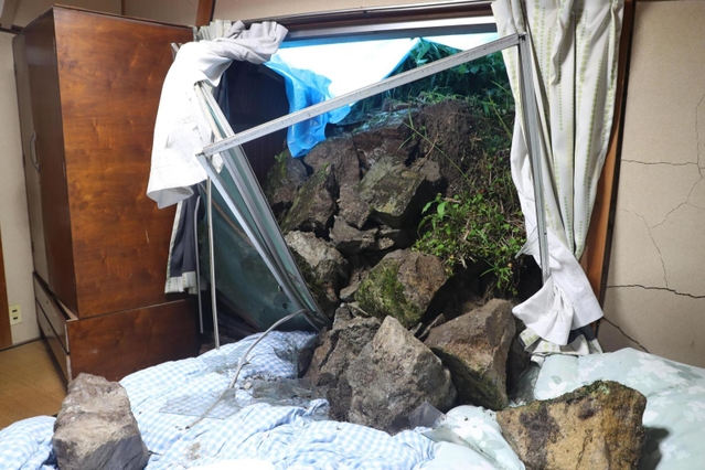 民家裏の石垣が崩れ、窓ガラスを割って寝室に流れ込んだ＝２日午後０時２８分、姫路市的形町的形（撮影・辰巳直之）
