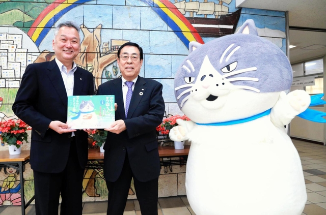 勝野哲也社長（中央）から絵本を受け取る小山光一校長＝神戸市須磨区堀池町１
