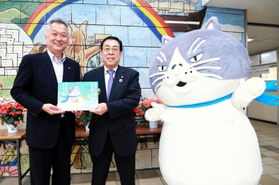 勝野哲也社長（中央）から絵本を受け取る小山光一校長＝神戸市須磨区堀池町１