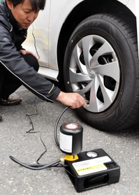 住友ゴム工業のパンク修理キット。自動車のシガーソケットにつないでコンプレッサーのスイッチを入れると、自動で修理剤と空気がタイヤに注入される＝伊丹市瑞穂町２