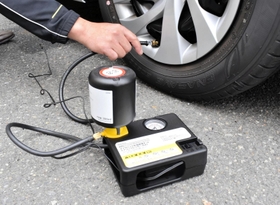 住友ゴム工業のパンク修理キット。自動車のシガーソケットにつないでコンプレッサーのスイッチを入れると、自動で修理剤と空気がタイヤに注入される＝伊丹市瑞穂町２