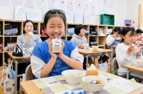 給食で創作童話「かなしきデブ猫ちゃん」のイラストが入った牛乳を飲む児童たち＝灘の浜小学校