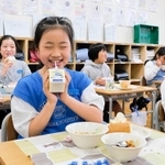 給食で創作童話「かなしきデブ猫ちゃん」のイラストが入った牛乳を飲む児童たち＝灘の浜小学校