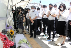 歩道橋事故の遺族・下村誠治さんの体験を聞き、慰霊碑に手を合わせる新人の明石市職員＝明石市大蔵海岸通１、朝霧歩道橋