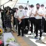 歩道橋事故の遺族・下村誠治さんの体験を聞き、慰霊碑に手を合わせる新人の明石市職員＝明石市大蔵海岸通１、朝霧歩道橋