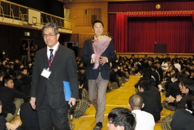 母校の宝塚中学校で講演後、花束を贈られて会場を後にするロッテ２軍監督の今岡真訪氏（中央）＝宝塚市美座１