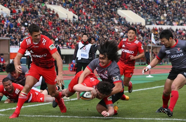 神戸製鋼-キヤノン　前半、相手にタックルされながらもトライを決める神戸製鋼のリチャード・バックマン（手前中央）＝１２日午後、神戸市須磨区のユニバー記念競技場（撮影・辰巳直之）