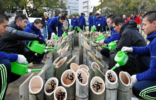 神港学園の部員とボランティア活動に取り組む北原光広前監督（右から２人目）と長男直也監督（左から２人目）＝１６日午後、神戸市中央区の東遊園地