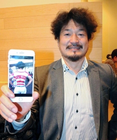 「ＯＮＥ　ＴＥＡＭ」とボディーペイントされた写真を手に笑顔を見せる森山漠さん＝大阪市内
