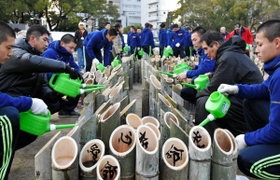 神港学園の部員とボランティア活動に取り組む北原光広前監督（右から２人目）と長男直也監督（左から２人目）＝１６日午後、神戸市中央区の東遊園地