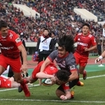 神戸製鋼-キヤノン　前半、相手にタックルされながらもトライを決める神戸製鋼のリチャード・バックマン（手前中央）＝１２日午後、神戸市須磨区のユニバー記念競技場（撮影・辰巳直之）