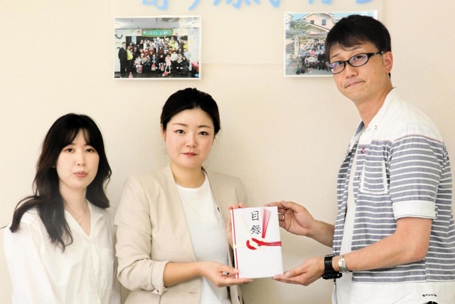 寄付金の目録を長田こどもホームの王子光仁施設長（右）に手渡すイ・ボミの李彩瑛マネジャー（中央）ら＝神戸市長田区