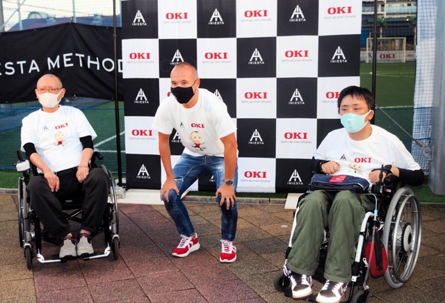車いす利用者とともに記念撮影に納まるイニエスタ選手（中央）＝神戸市東灘区向洋町中８