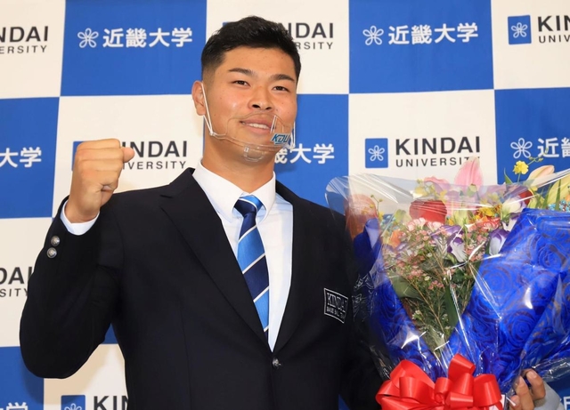 ４球団から１位指名されて阪神との交渉が決まり、花束を手にガッツポーズをする佐藤輝明選手＝２６日午後、大阪府東大阪市小若江３、近畿大学東大阪キャンパス（撮影・斎藤雅志）