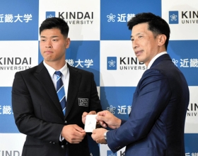 交渉権獲得カードを手に、阪神・矢野燿大監督（右）と記念撮影する近大の佐藤輝明内野手＝２７日午後、大阪府東大阪市の近畿大学