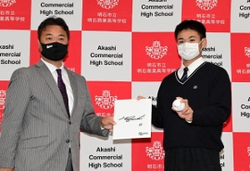 ロッテの永野吉成プロ・アマスカウト部長（左）から井口資仁監督のサインボールと色紙を受け取る明石商高の中森俊介投手＝明石市の同校（撮影・中西幸大）