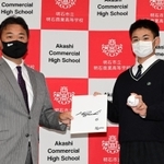 ロッテの永野吉成プロ・アマスカウト部長（左）から井口資仁監督のサインボールと色紙を受け取る明石商高の中森俊介投手＝明石市の同校（撮影・中西幸大）