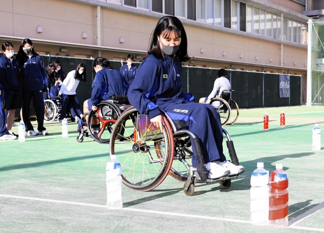 車いすに乗り、陸上スラロームを体験する女子生徒＝神戸市兵庫区会下山町３、神港橘高校