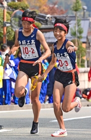 女子・西脇工の２区久保希蘭々（左）からたすきを受け取り走り出す３区宗佐菜々実（撮影・秋山亮太）