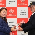 オリックスの乾絵美スカウト（左）から中嶋聡監督代行と吉田正尚外野手のサインボールを受け取るを明石商の来田涼斗外野手＝２日、明石市の同校（撮影・鈴木雅之）