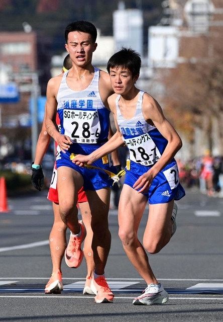 男子・須磨学園の６区国安広人（左）からたすきを受け走り出すアンカー八沢輝人＝２０日午後、京都市中京区（撮影・秋山亮太）