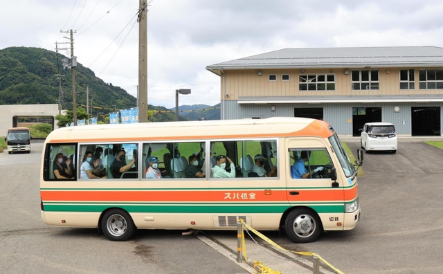 バスで練習場に到着し、報道陣に手を振るドイツのボート選手たち＝３日午前、豊岡市城崎町今津（撮影・吉田敦史）