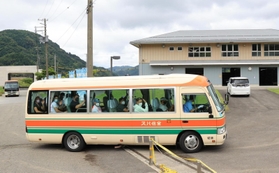 バスで練習場に到着し、報道陣に手を振るドイツのボート選手たち＝３日午前、豊岡市城崎町今津（撮影・吉田敦史）