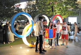 東京五輪の開会式が終わり、国立競技場前の五輪マークのモニュメントで記念撮影する人たち。周辺は多くの人であふれかえった＝２４日午前０時２２分、東京都新宿区