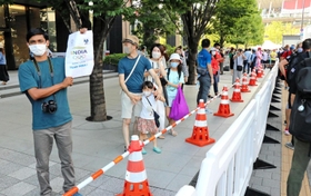 東京五輪の開会式前、国立競技場近くでインドを応援する紙を掲げる人。記者とも目が合い、互いにうなずき合った＝２３日午後５時２２分、東京都新宿区