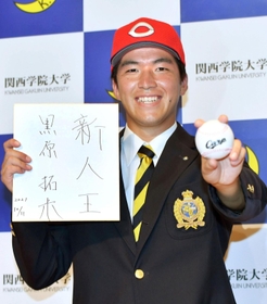 広島から１位指名され、「新人王」の色紙を手に笑顔を見せる関学大の黒原拓未＝西宮市の同大学（撮影・佐々木彰尚）