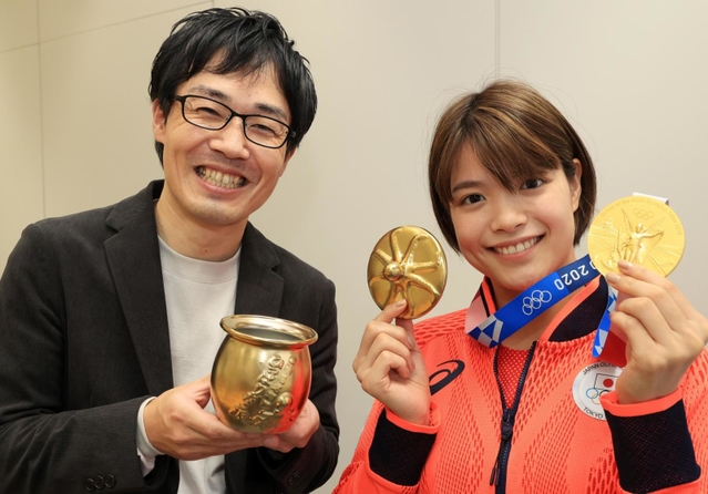 淡路屋名物「ひっぱりだこ飯」の特製“金のふた”を受け取り、と金メダルと一緒に掲げる東京五輪金メダリストの阿部詩選手（右）＝神戸新聞社（撮影・鈴木雅之）