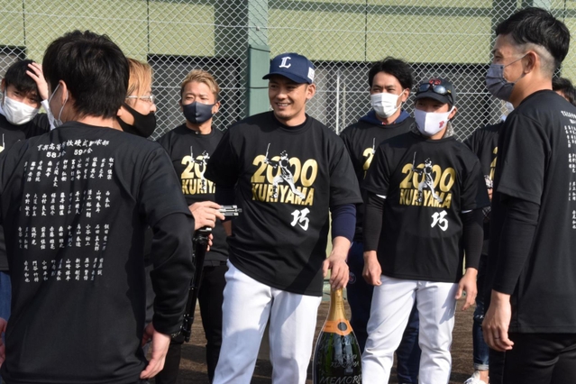 母校・育英高野球部の同級生らに記念品を贈られ、笑顔を見せる西武・栗山（中央）＝三木市、三木総合防災公園野球場